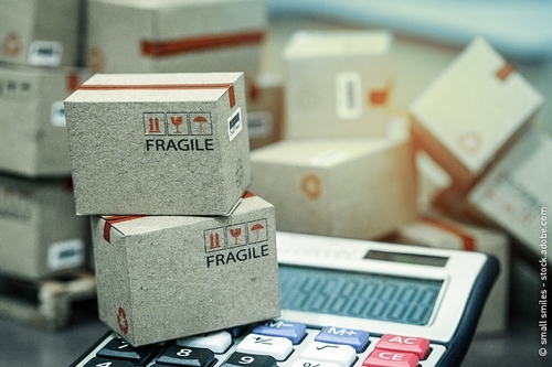 Cajas de transporte descansan sobre una calculadora para estimar los costes de transporte.